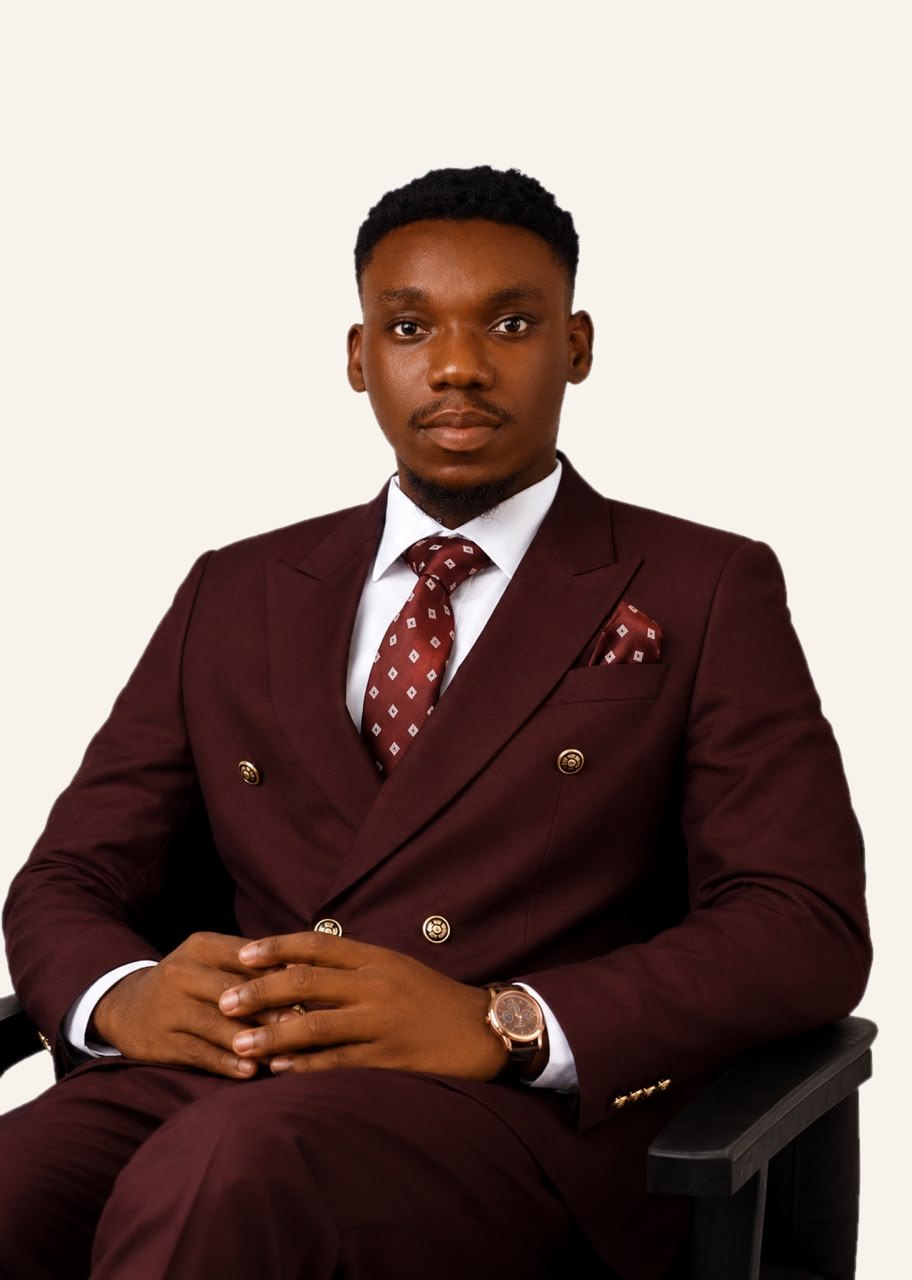Akinmboni Marcus O. seated, wearing a burgundy double-breasted suit